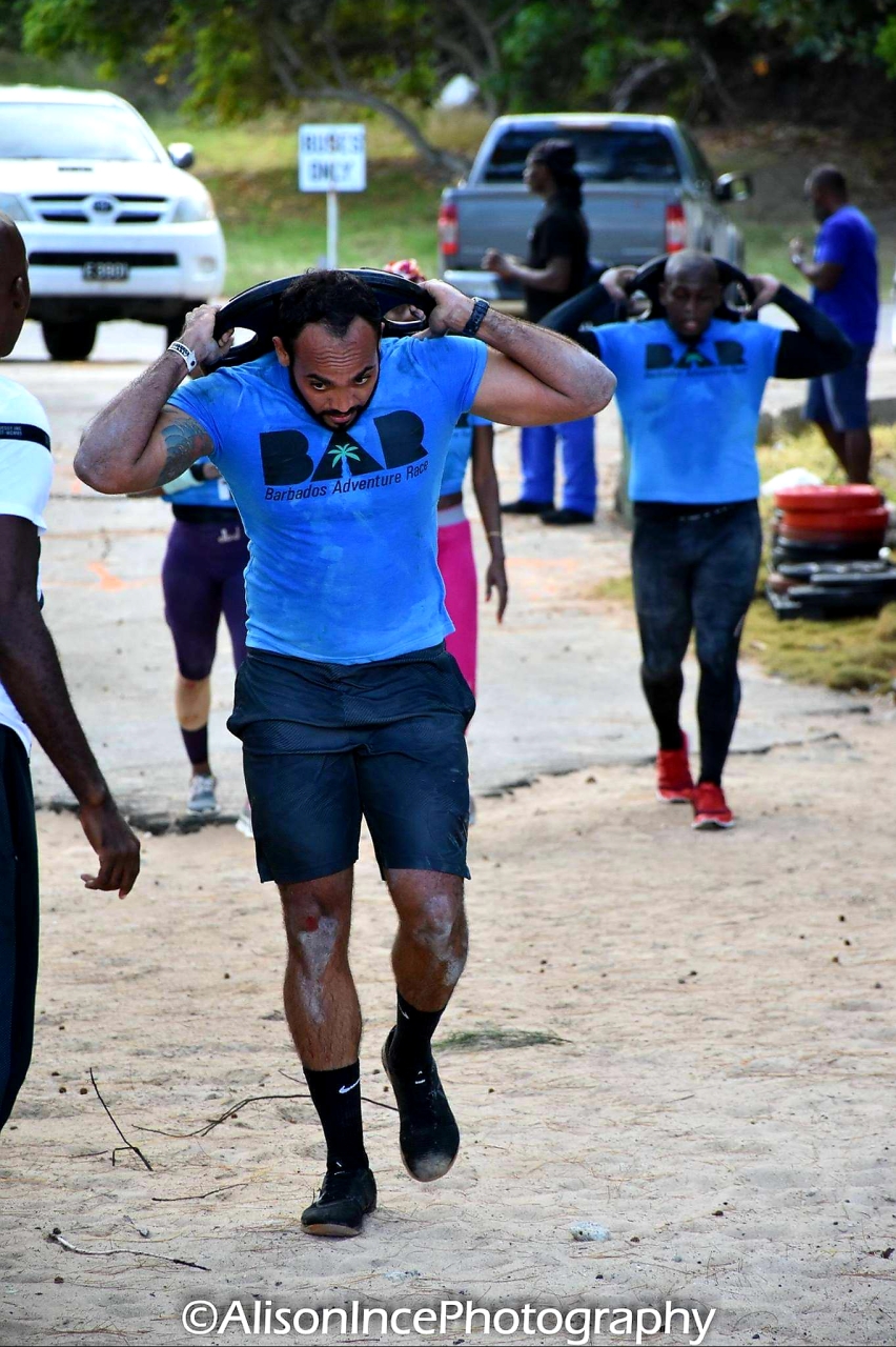 Asokore Beckles competing in the Barbados Adventure Race carrying a weight plate